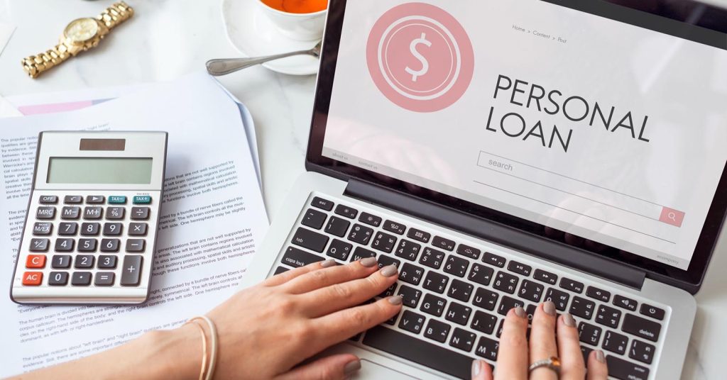 Person reviewing personal loan options and APR on a laptop with financial documents and calculator