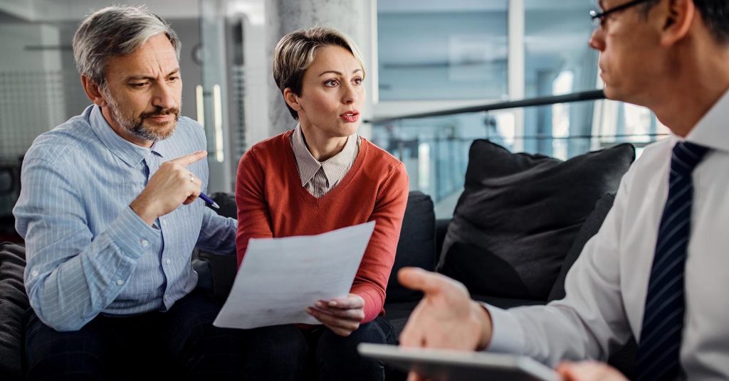 Two people reviewing a document during a discussion with another person