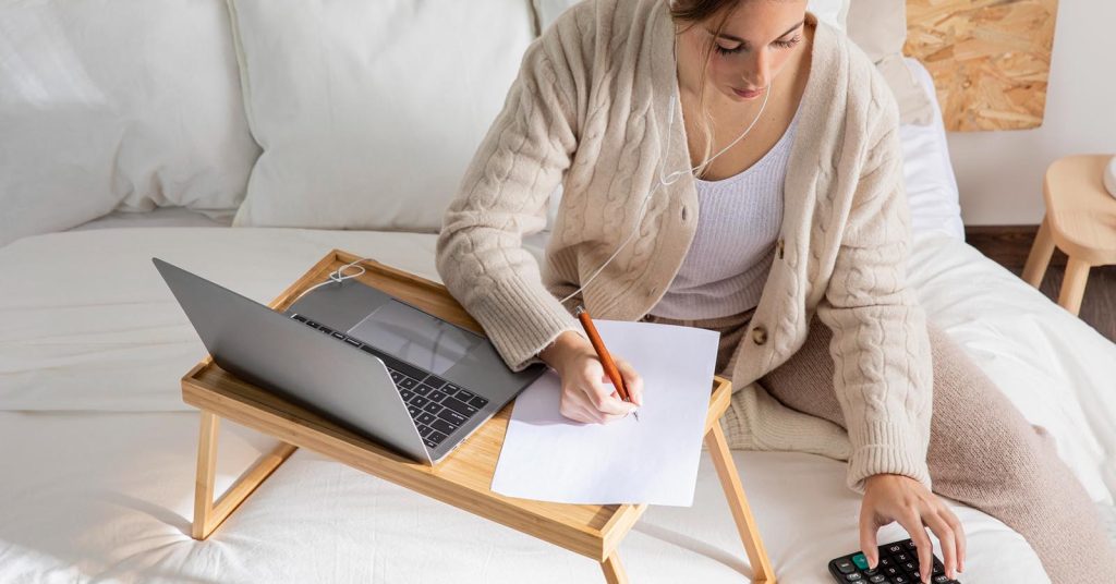Woman reviewing household finances with a calculator and laptop