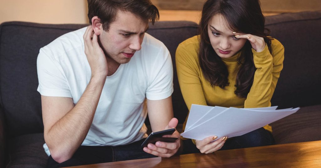 Couple reviewing a debt collection notice and financial documents on the sofa