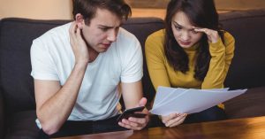 Couple reviewing a debt collection notice and financial documents on the sofa
