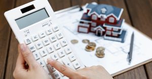 Calculator next to a house model for estimating mortgage closing costs