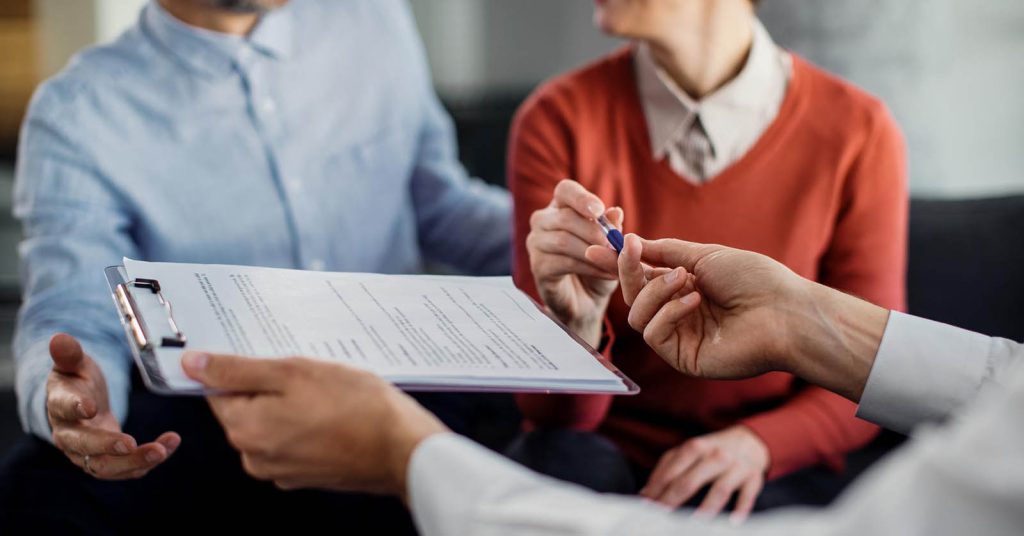Couple reviewing and signing loan documents with a financial advisor