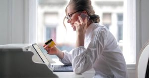 Woman holding a credit card while comparing borrowing options online