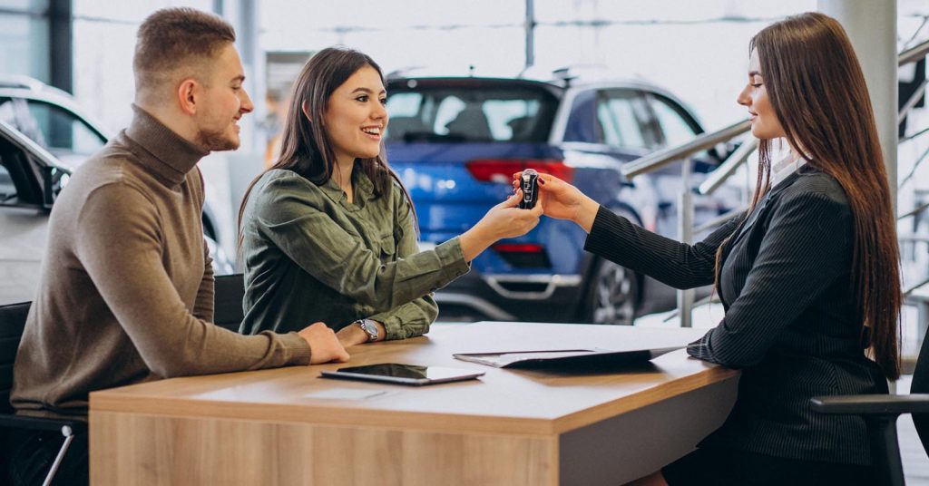 Couple discussing car financing options with a dealership salesperson