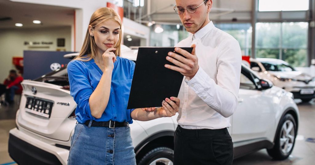 Woman comparing cars in a showroom while planning an affordable auto loan budget