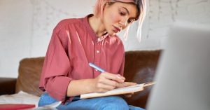 Borrower reviewing private student loan payment options and making notes at home
