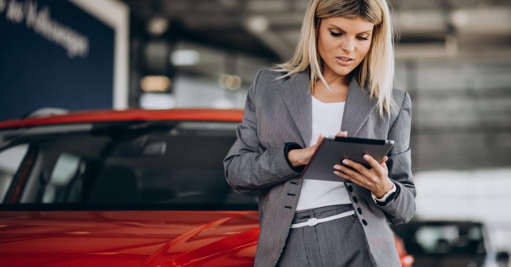 Woman reviewing car loan term options on a tablet in a showroom