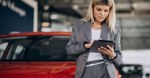Woman reviewing car loan term options on a tablet in a showroom