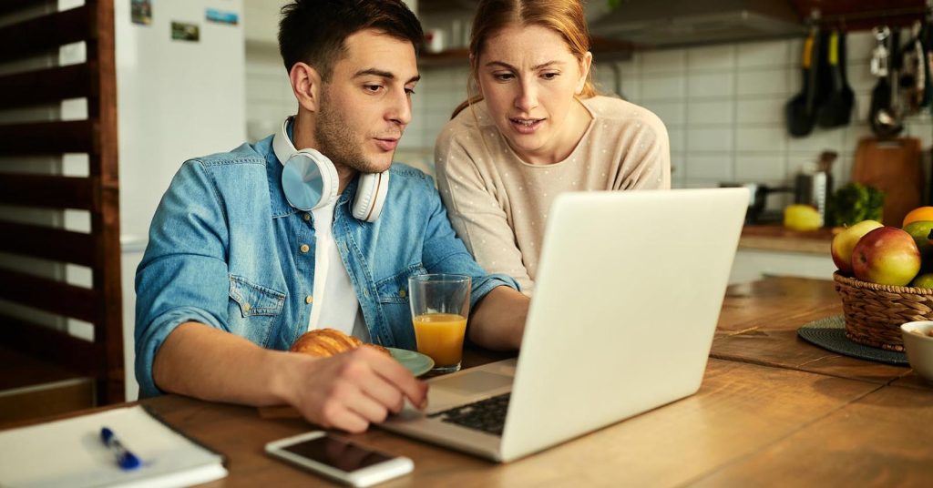Couple reviewing a frozen bank account and debt levy notice on a laptop