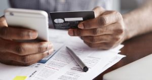 Woman holding a credit card and phone while reviewing a credit card bill
