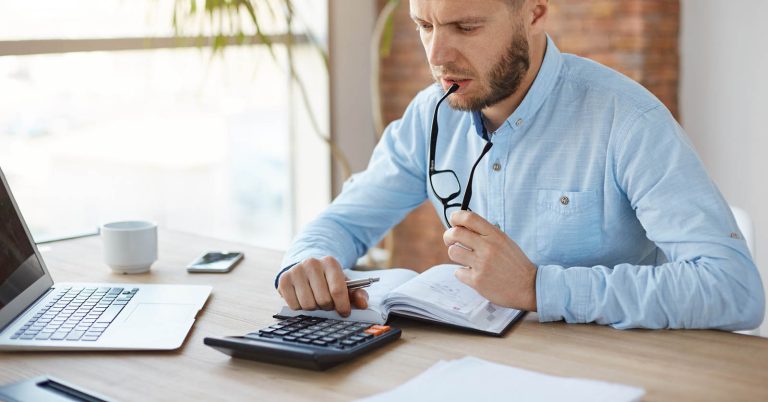 Man using a calculator while reviewing a debt consolidation loan offer