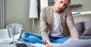 Man calling a credit card issuer about a hardship program while reviewing bills
