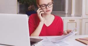 Woman calling a debt collector while reviewing debt buyer and collection agency paperwork