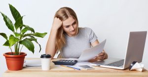 Woman reviewing bills and comparing debt consolidation and debt settlement options