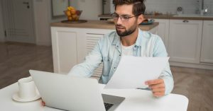 Man reviewing debt relief paperwork and credit information on a laptop
