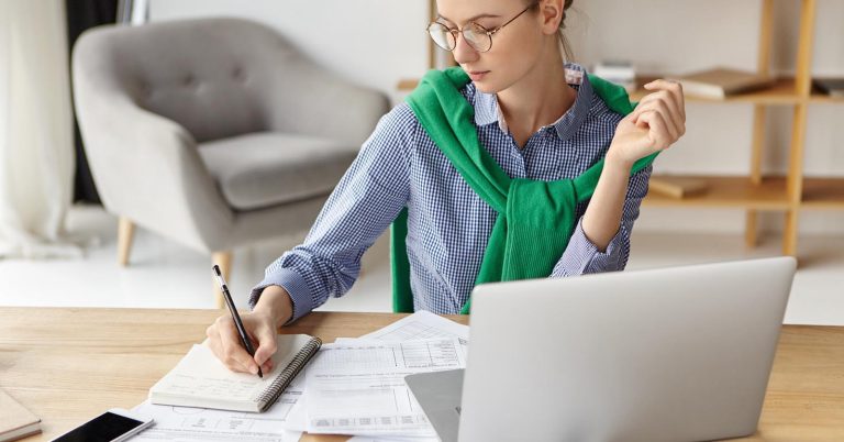 Woman reviewing bills and making a debt payoff plan at a laptop