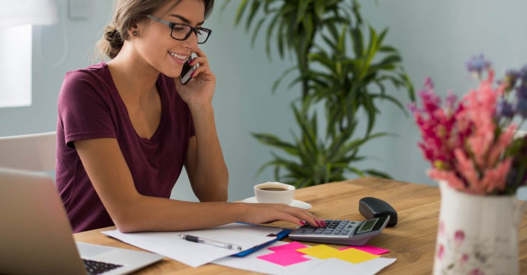 Woman using a calculator while planning how to pay off credit card debt faster