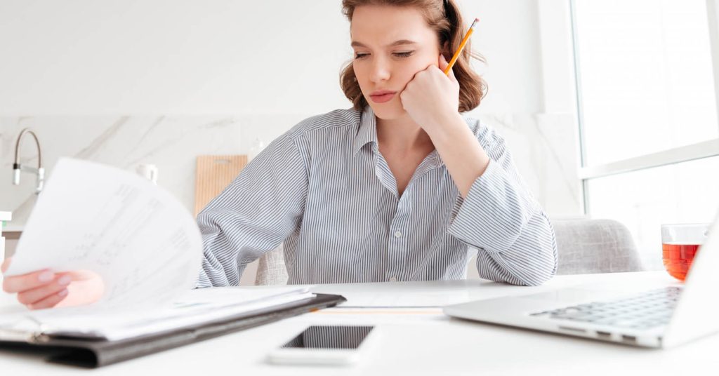 Woman reviewing credit card payment paperwork and comparing minimum versus fixed payments
