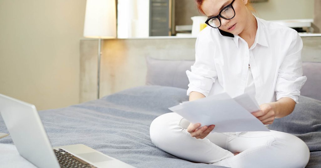 Woman calling a medical billing office while reviewing medical bill paperwork