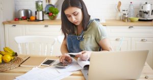 Woman using a calculator while reviewing debt payment paperwork