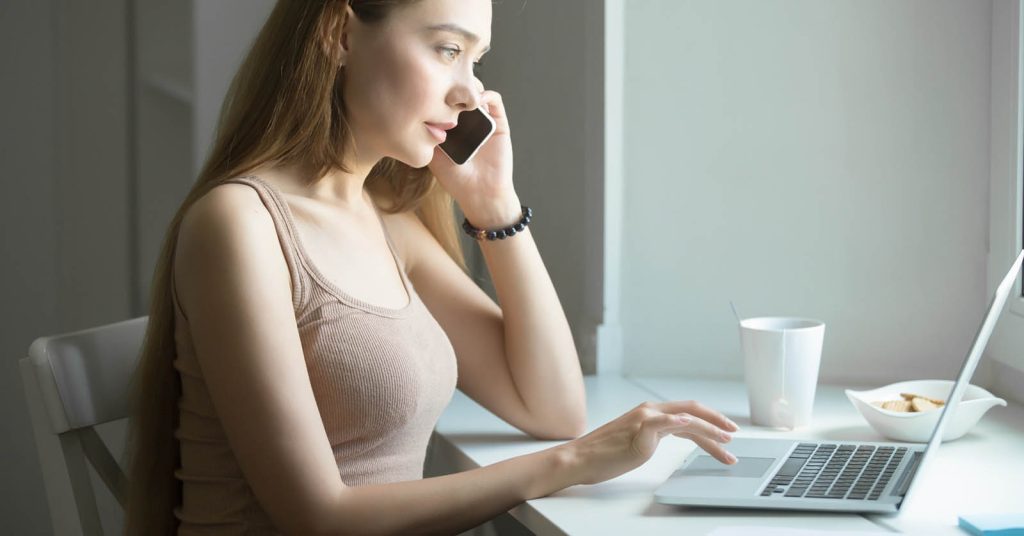 Woman calling a creditor or collection agency while checking debt information online
