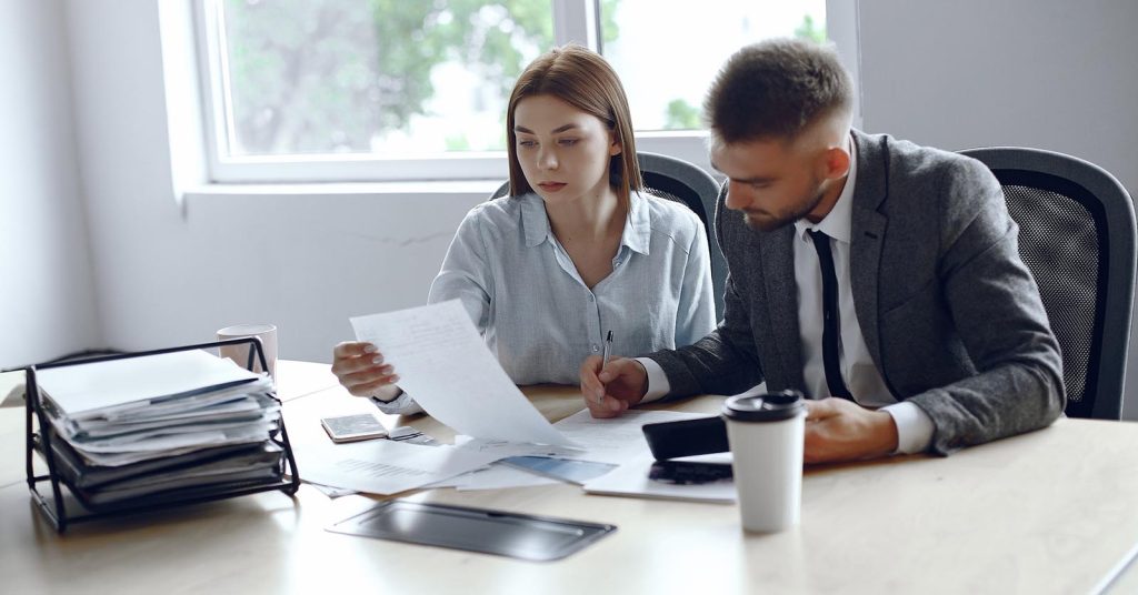 Two people reviewing financial documents at an office desk