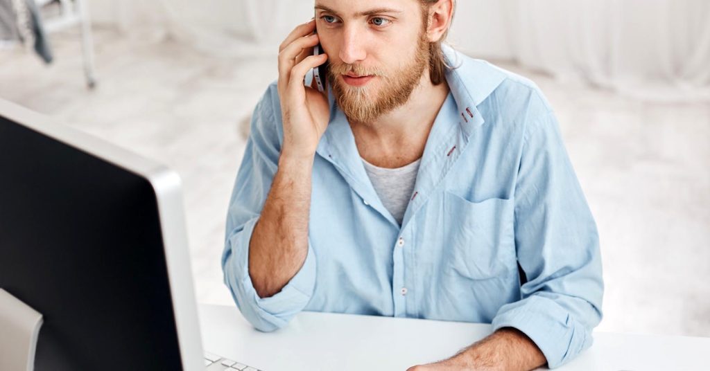Man speaking on the phone while reviewing credit card debt information on a computer