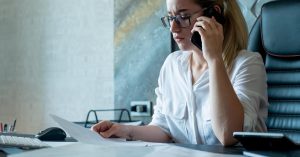 Concerned woman reviewing an unfamiliar debt collection notice during a phone call