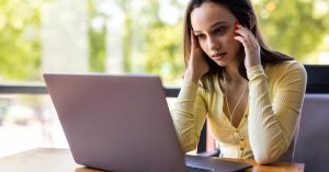 Stressed woman reviewing repeated debt collection messages on her laptop