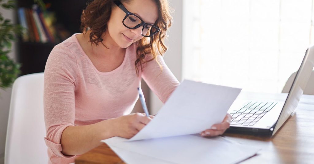 Woman preparing a debt validation letter while reviewing collection documents