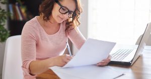 Woman preparing a debt validation letter while reviewing collection documents