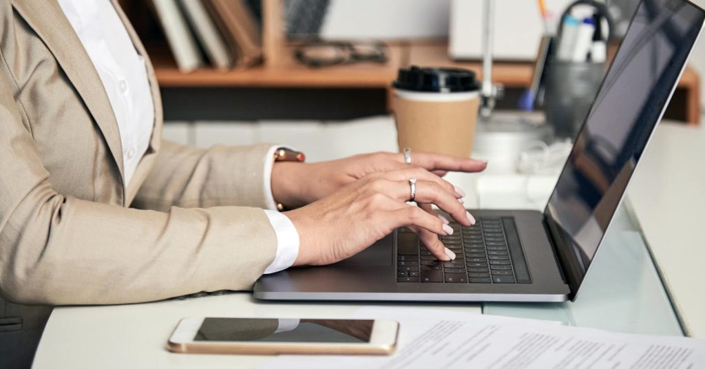 Woman filing a credit report dispute online with collection documents on her desk