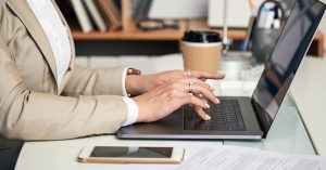 Woman filing a credit report dispute online with collection documents on her desk