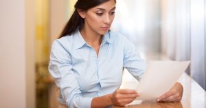 Woman reviewing a credit report to check when a collection account should be removed