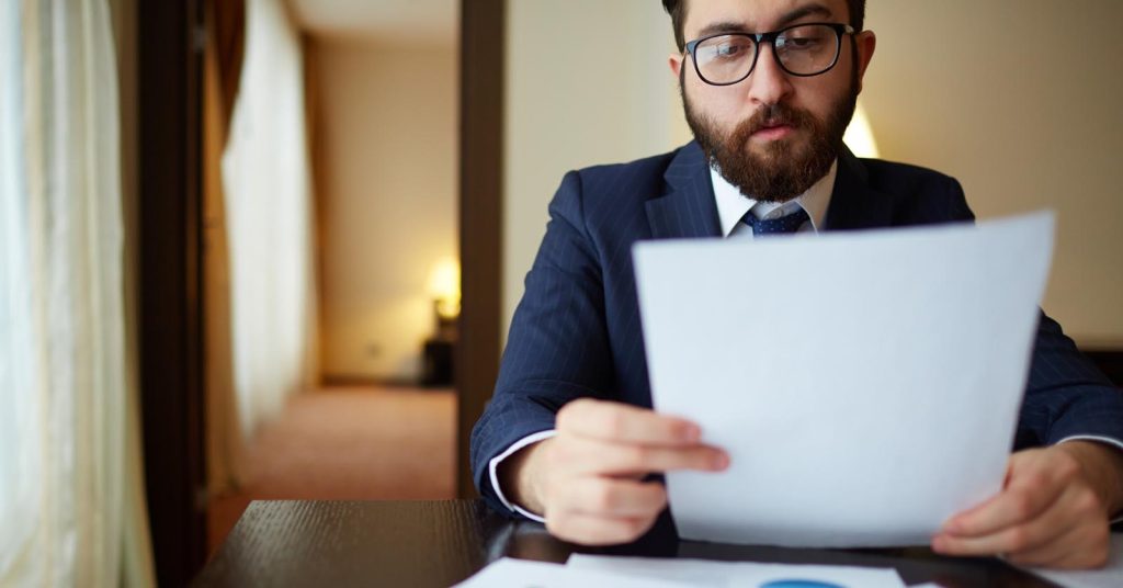 Man reviewing credit card statements to decide whether his debt is becoming unmanageable