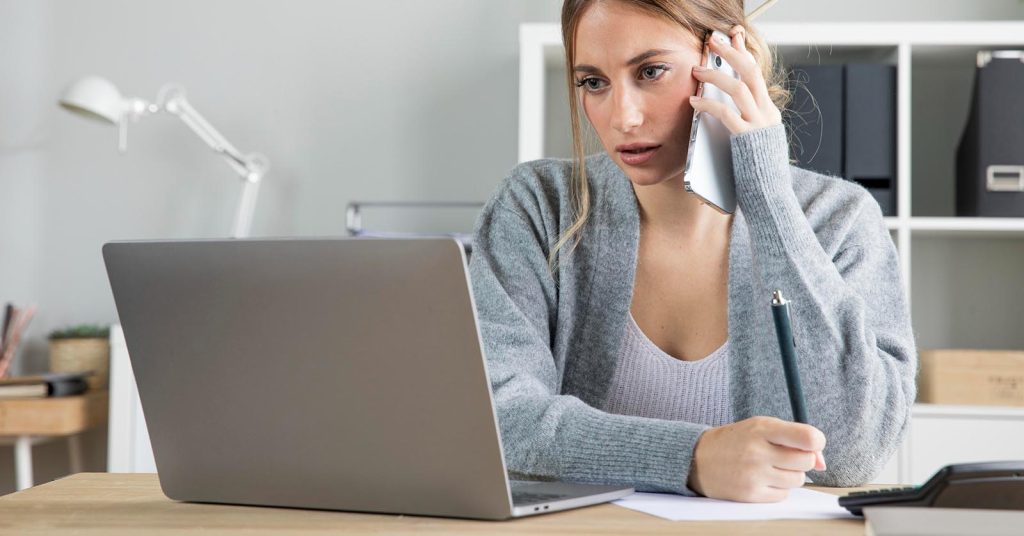 Woman reviewing a budget during a phone call about debt repayment
