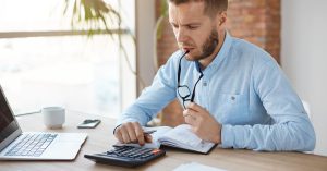 Man reviewing household finances with a calculator and notebook