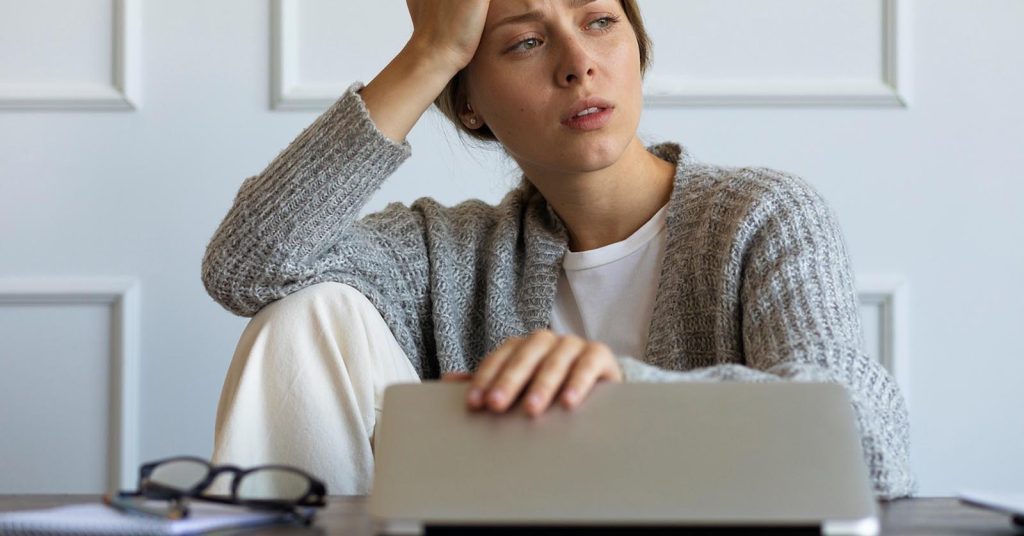 Concerned woman reviewing a suspicious side hustle or remote job offer on a laptop
