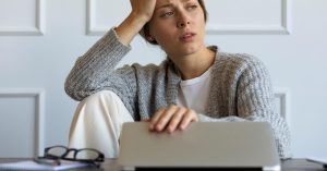 Concerned woman reviewing a suspicious side hustle or remote job offer on a laptop