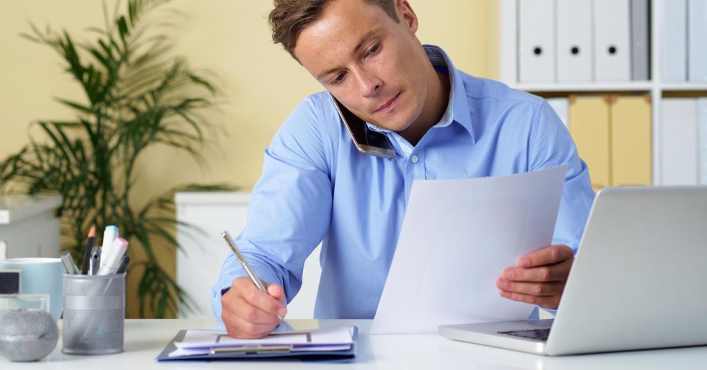 Man reviewing balance transfer credit card terms while speaking by phone