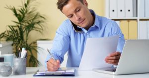 Man reviewing balance transfer credit card terms while speaking by phone