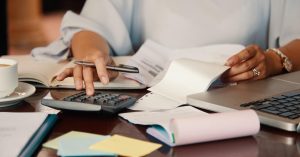 Woman reviewing bills with a calculator and laptop