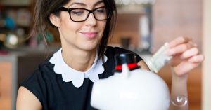 Woman putting money into a piggy bank at home