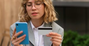 Young adult reviewing a credit card while using a phone