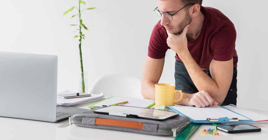 Man comparing debt consolidation costs and repayment options at a desk