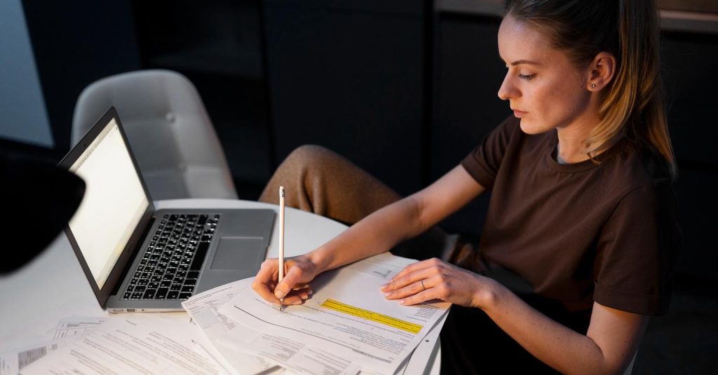 Woman using a laptop with financial data displayed behind her