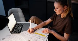 Woman using a laptop with financial data displayed behind her