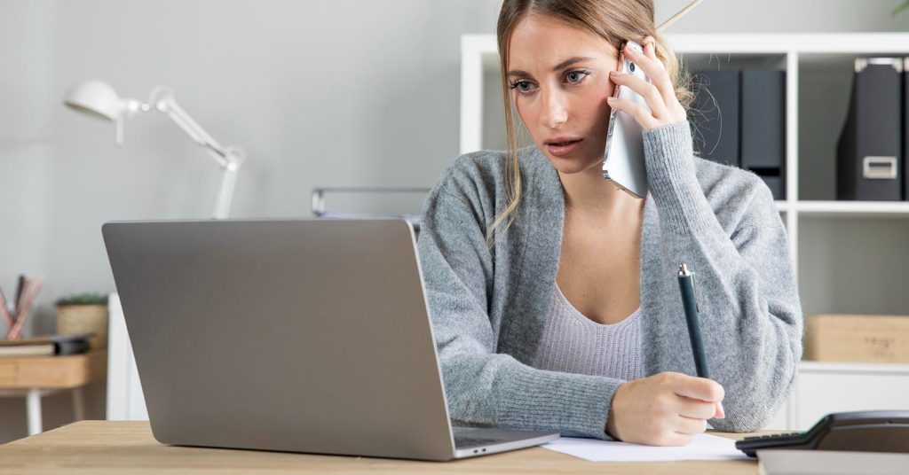 Concerned woman on the phone while reviewing information on a laptop
