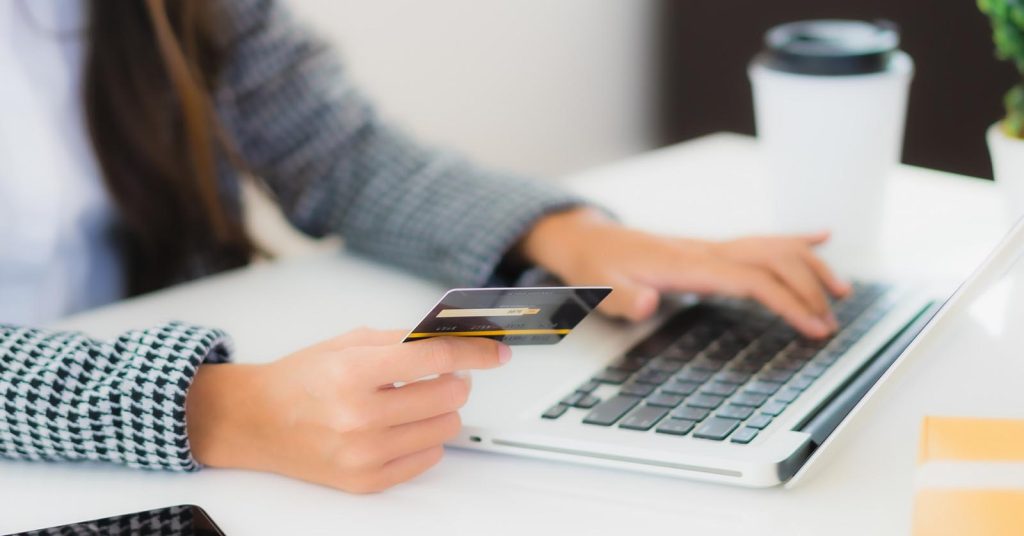 Woman reviewing financial information on a laptop while holding a credit card